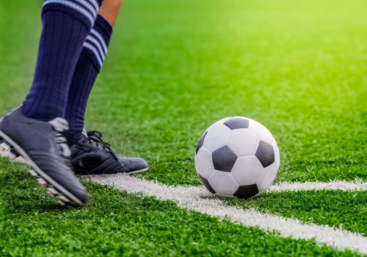A soccer ball is on the ground near a foot.